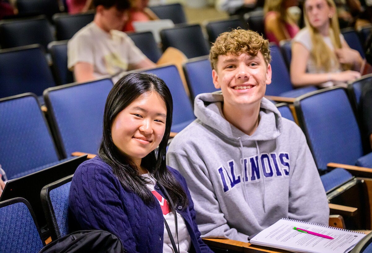 Two students smile for a photo while sitting next to each other in Foellinger Auditorium.