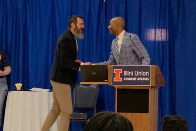 DiIanni shakes hands with Provost Kevin Jackson as he accepts the 2026 Equity Champion Instructor Award.