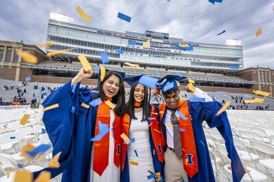 Confetti rains on three students as they celebrate their graduation ceremony at Gies Memorial Stadium.