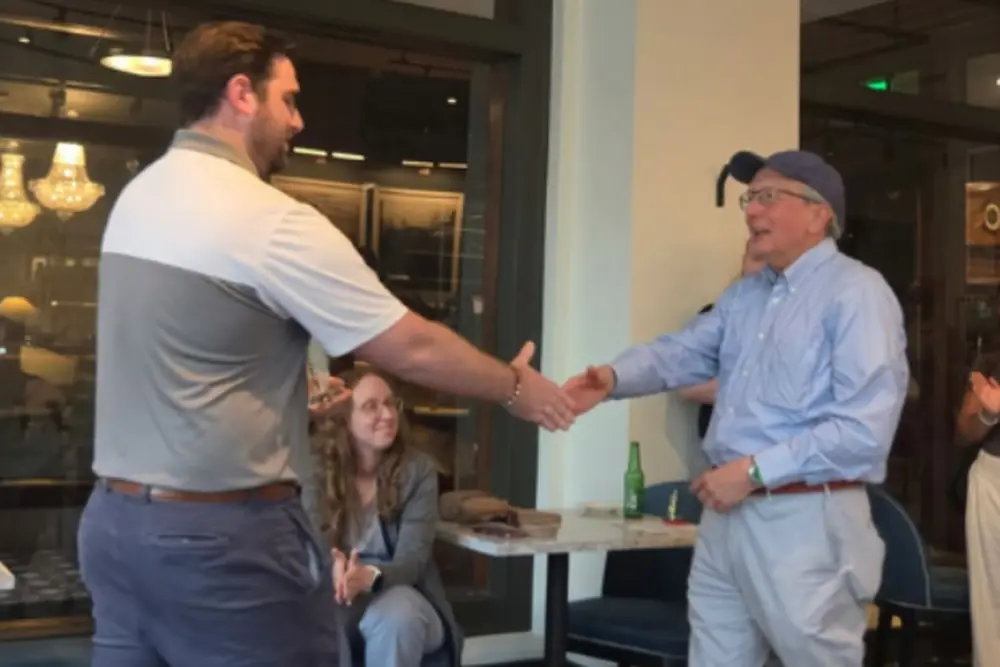 Morris Kleiner shakes hands with a presenter as he accepts his lifetime achievement award.