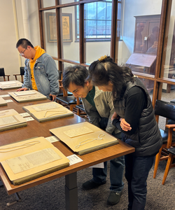 Two people looking over a table at handwritten letters from Adam Smith and other prominent economists.