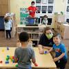 In this May 27, 2020, photo, teachers Jana Blair, right, and Aaron Rainboth, upper-center, wear masks as they work with kids at the Frederickson KinderCare daycare center, in Tacoma, Wash.